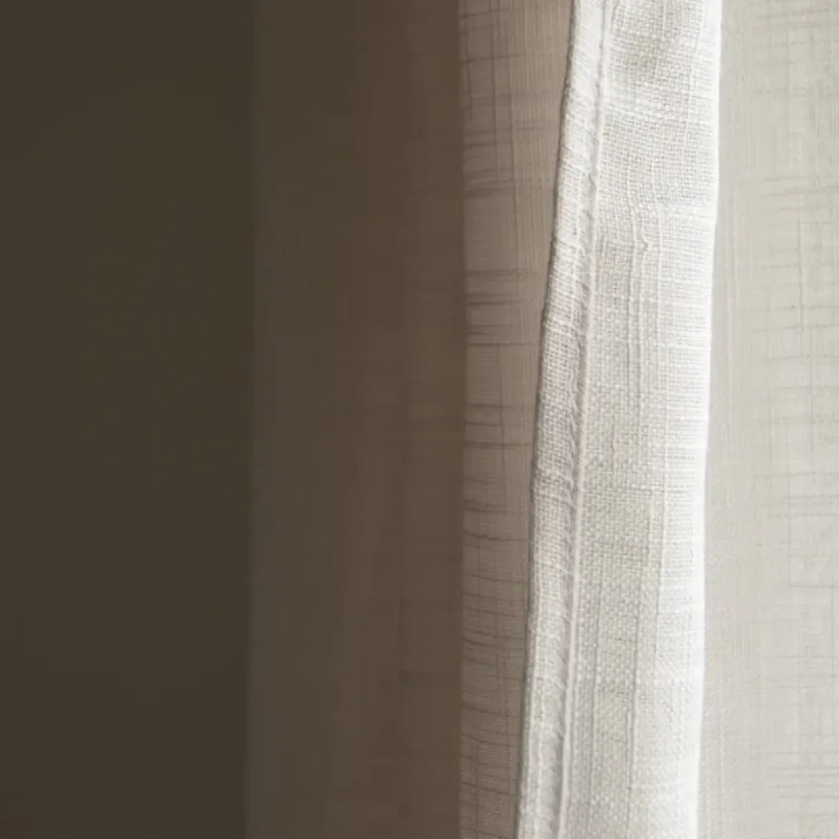 Cortinas de lino beige claro con textura sutil en una ventana, iluminadas por la luz natural, en un proyecto en Sicilia