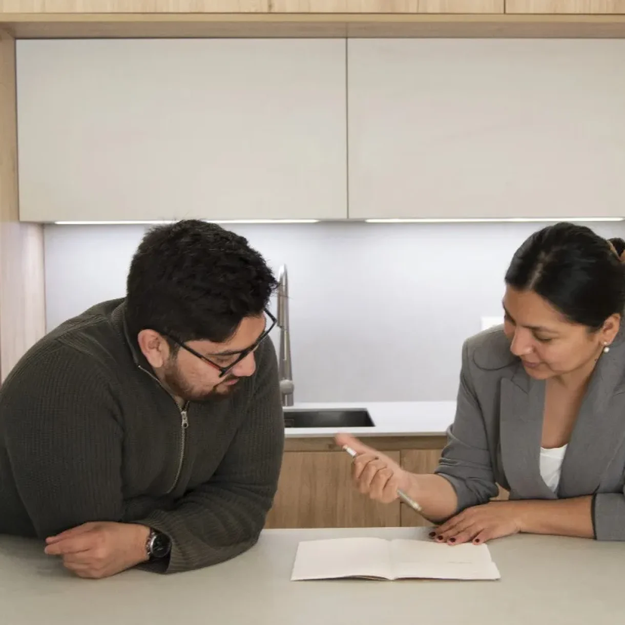 Hombre y mujer revisando documentos en una cocina moderna, discutiendo detalles del proyecto Sicília en Barcelona.