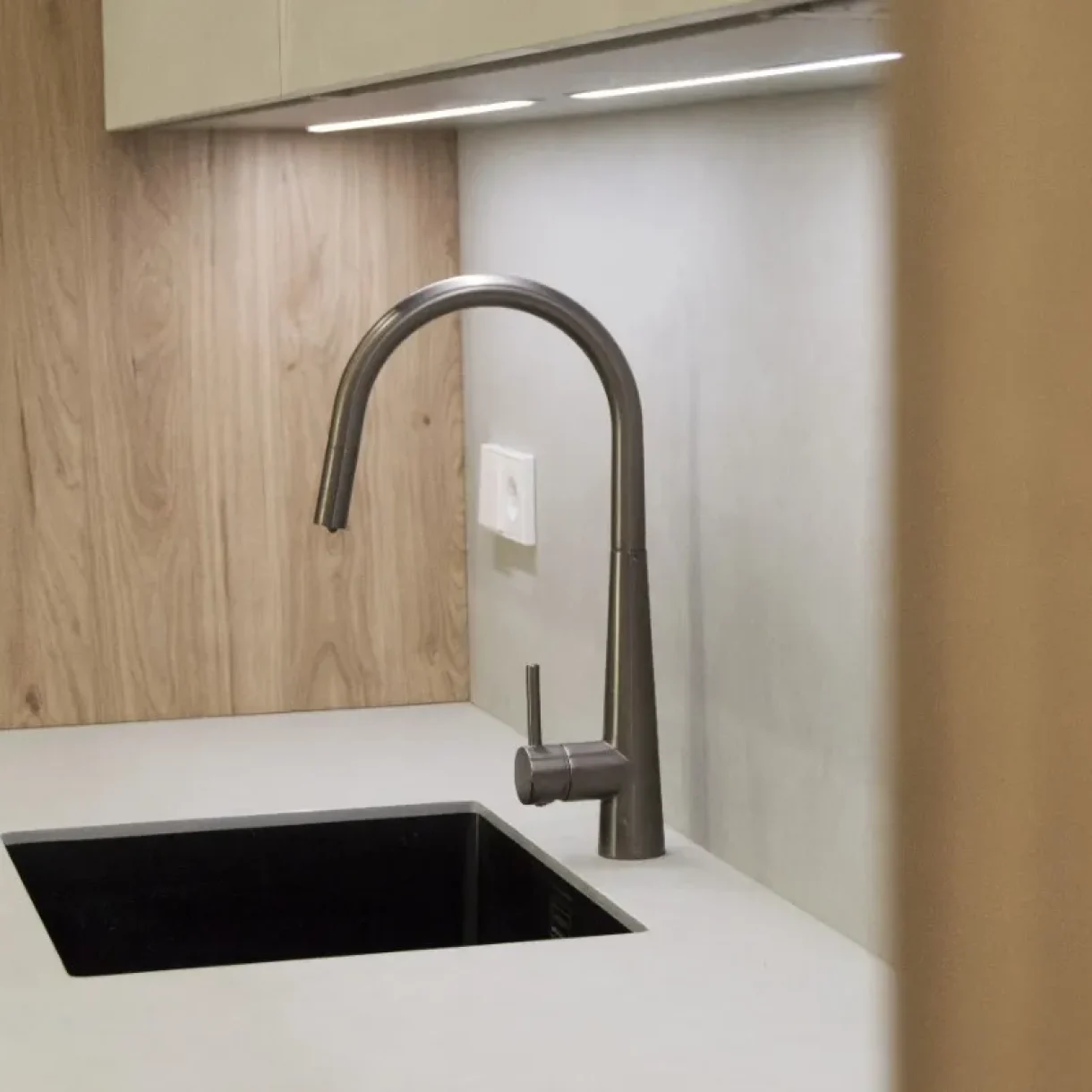 Grifo de cocina moderno en acabado oscuro sobre fregadero negro y encimera blanca en proyecto Sicília