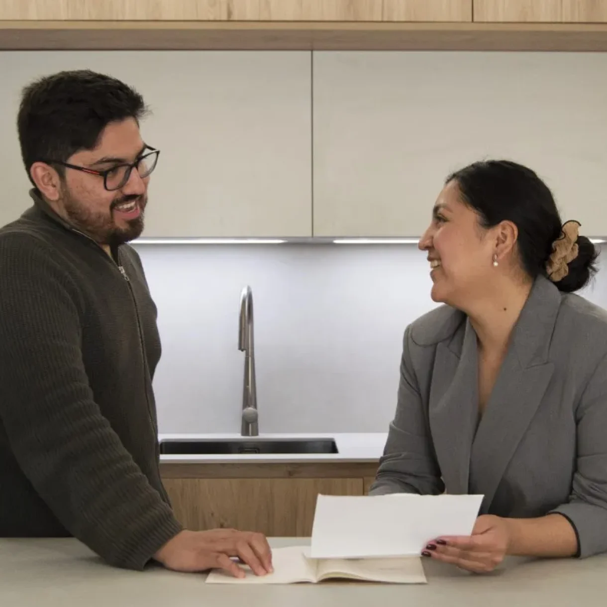 Pareja sonriente revisando documentos en una cocina moderna del proyecto Sicília en Barcelona