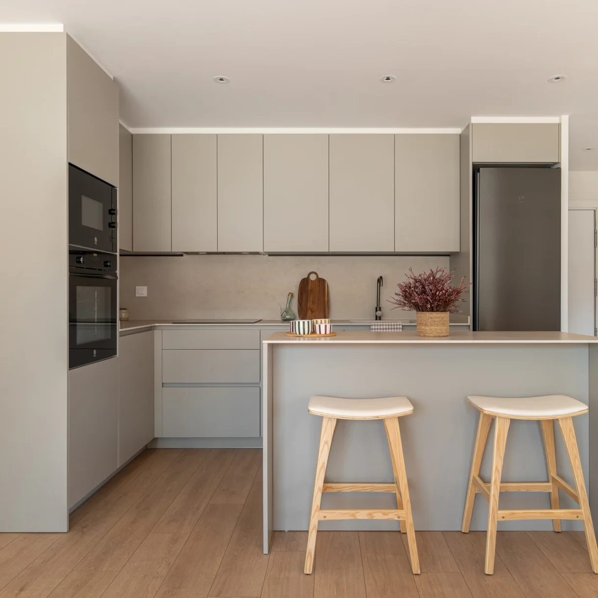 Cocina moderna en tonos grises con diseño elegante y funcional, equipada con electrodomésticos integrados. Muestra encimeras de piedra natural y armarios minimalistas para un hogar contemporáneo en Sant Andreu.