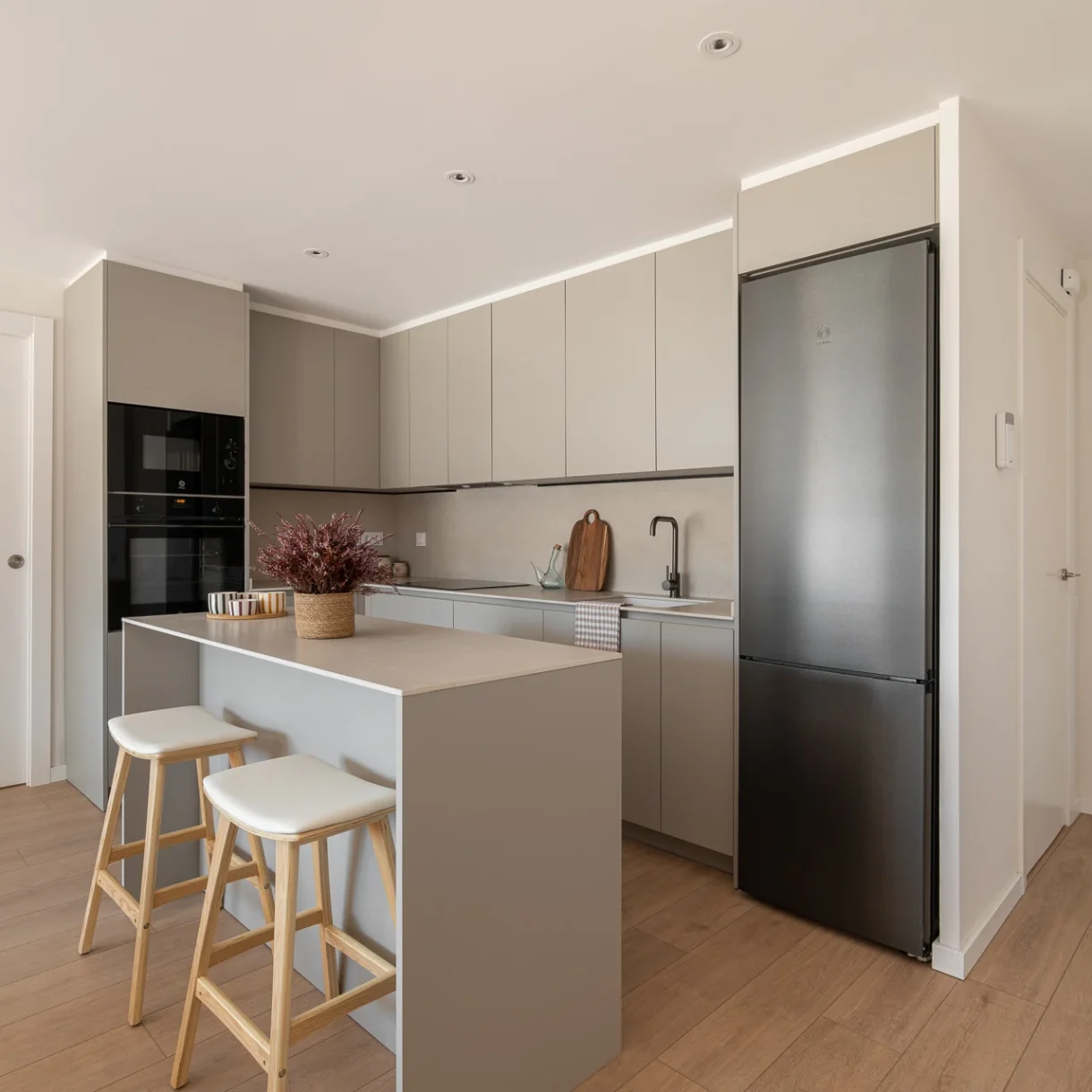 Cocina moderna de diseño con isla central, mobiliario blanco sin tiradores y encimera de mármol, en un proyecto de reforma integral en Sant Andreu.