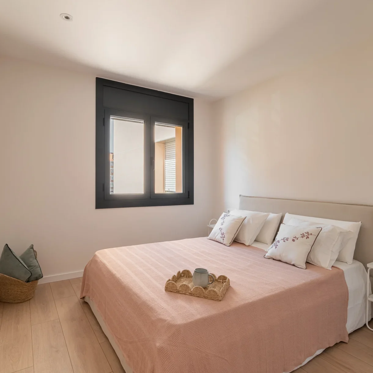 Dormitorio principal reformado en Sant Andreu, Barcelona, con cama doble y cabecero de madera claro, iluminación cálida y mesitas de noche funcionales. Diseño interior moderno y acogedor.