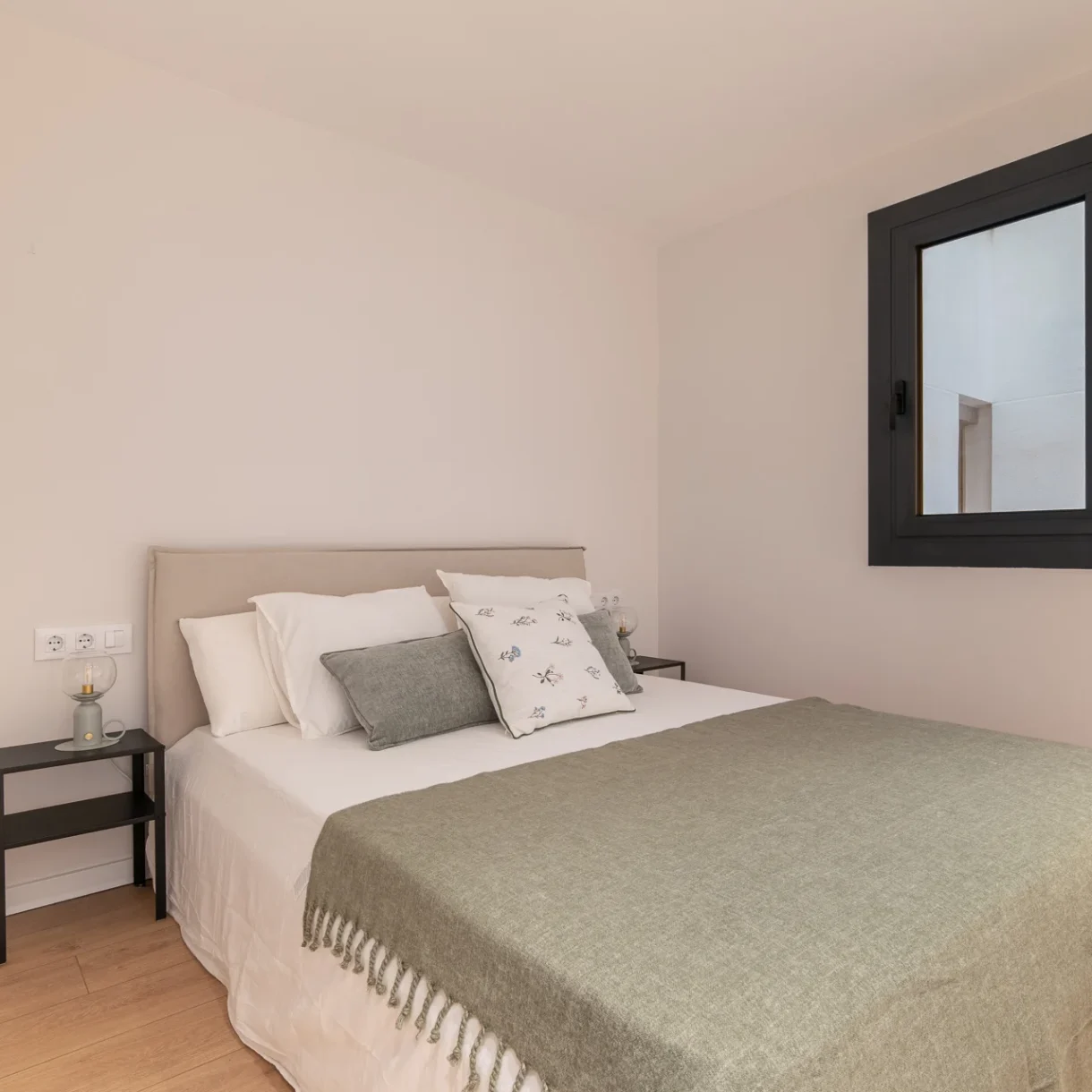 Dormitorio principal reformado en Sant Andreu, Barcelona, con cama doble, cabecero de madera, mesitas de noche y lámparas de lectura. Diseño moderno y funcional.