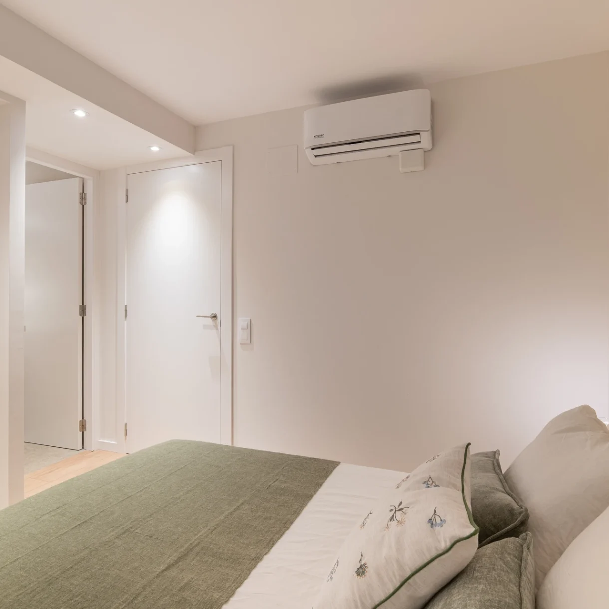 Dormitorio moderno en Sant Andreu, Barcelona, con cama de plataforma, cabecero tapizado y mesitas de noche flotantes, diseñado por profesionales.