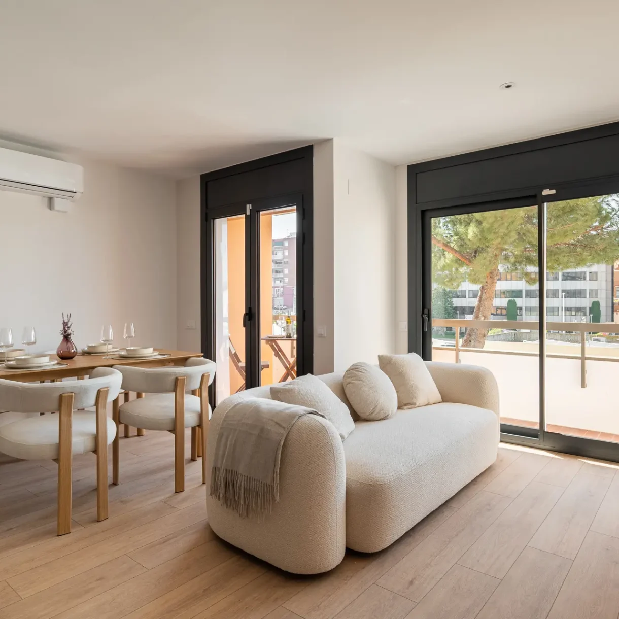 Salón comedor de diseño moderno integrado en un piso reformado, con mobiliario funcional y decoración minimalista en Sant Andreu.